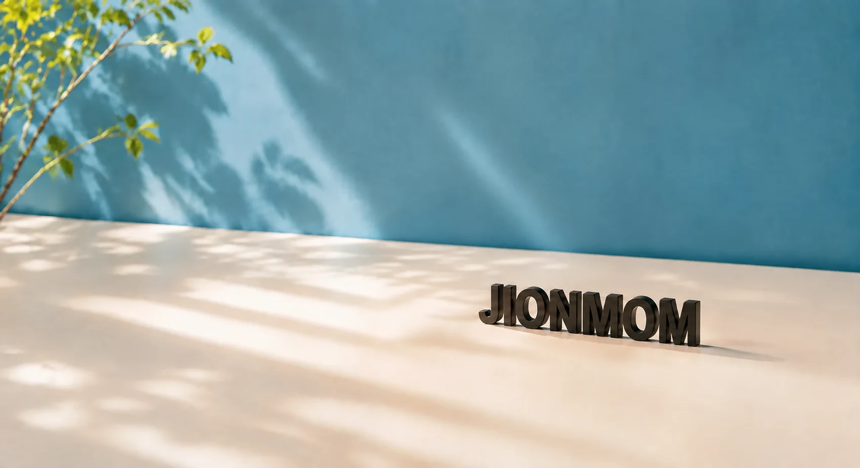 햇살과 나뭇잎 아래 놓인 작은 철제 JIONMOM 글자 조형물